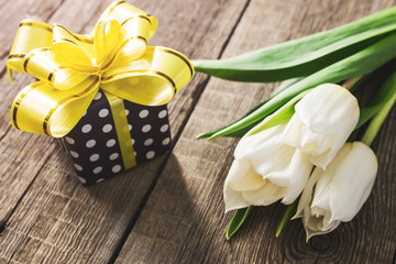 White tulips and gift box on wooden table