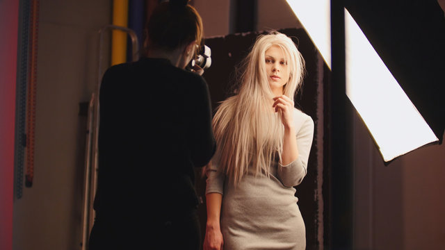 Professional photo session - blonde female model standing near studio flash - photographer's working