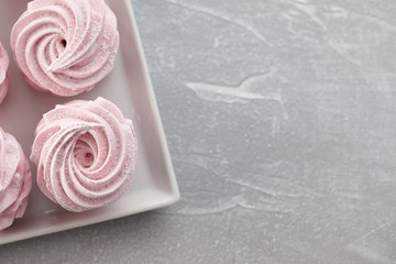Pink homemade zephyr or marshmallow in white plate on light gray stone background