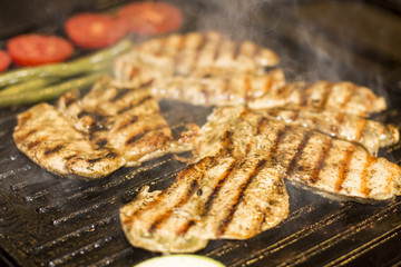 Grilled chicken breast with sausage, fries and salad on grill.