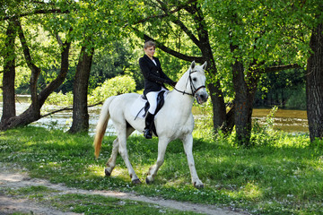 Beautiful girl galloping horse in summer park 