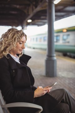 Woman sitting on platform using mobile phone