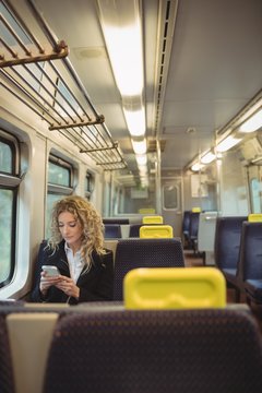 Woman using mobile phone inside train compartment