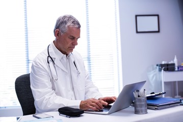 Doctor sitting at table and using laptop