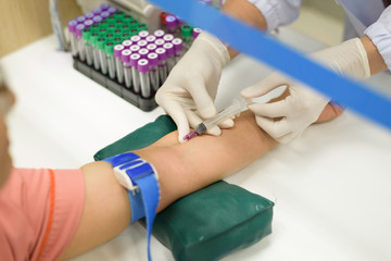 Close up nurse pricking needle into the patient arm for blood chemistry test.Laboratory with...