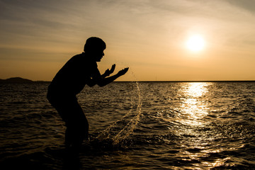 Silhouette of young playing in the river. © sorranop01