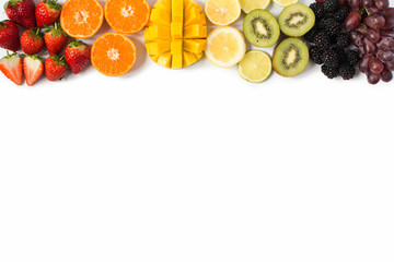 Top view of whole fruits and in the rows; red, orange, yellow, green fruits on the white background; grapefruit, mango, strawberries, orange, lemon, kiwi