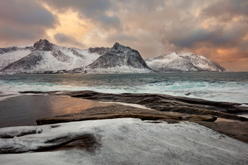 Unique winter sea landscape with dramatic sky and mountains