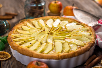 Homemade apple pie and ingredients on a rustic table
