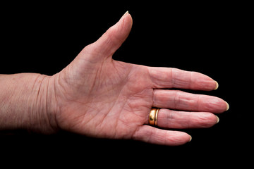 Mature woman's hand in greeting gesture. On black.