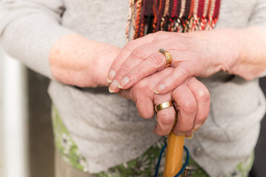 Close up of old woman's hands on umbrella handle.