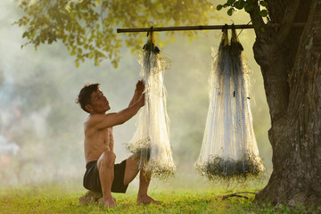 A fisherman casting repair the nets ,Thailand