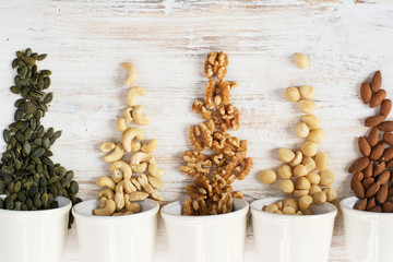 Nuts in bowls on the white wooden table