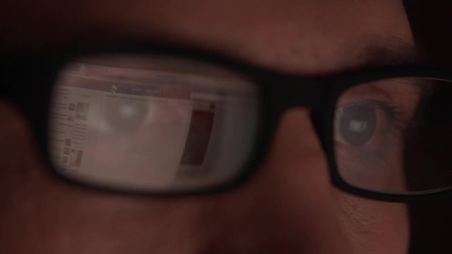 Website reflecting in glasses of Caucasian male. Close up footage in slowmotion