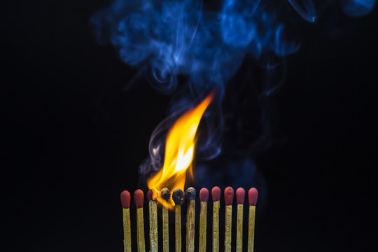 Closeup of burning matches on black background.
