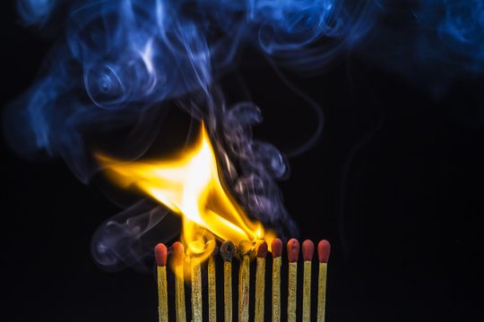 Closeup of burning matches on black background.