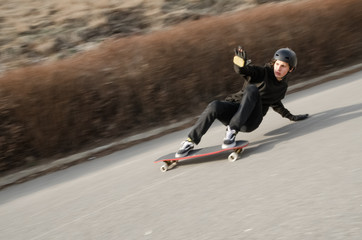 Young man in helmet is going to slide, slide with sparks on a longboard on the asphalt