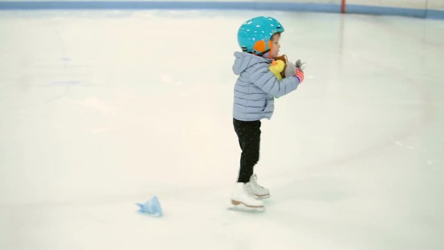 Toddler girl learning how to ice skate on in door ice arena
