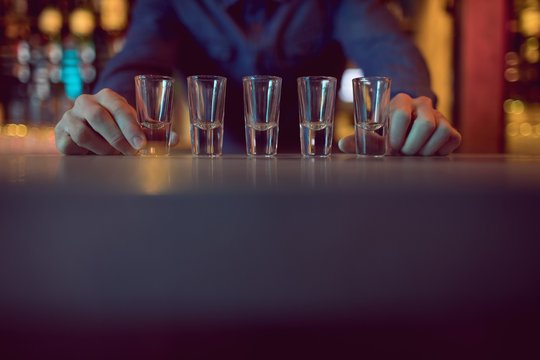Bartender placing shot glasses in a row at counter