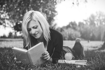 photo of student girl reading on grass