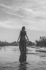 long-haired woman walking in the river shallow water