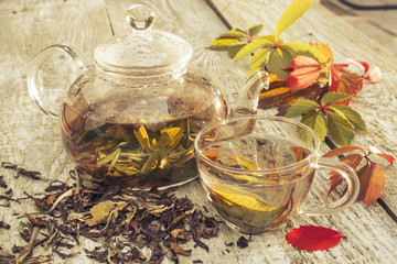 Fototapeta premium Glass teapot and cup with green tea on old wooden table. Glass teapot with tea.