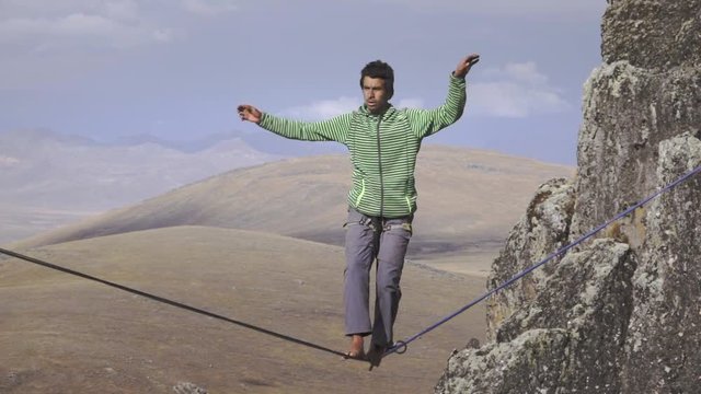 Highliner walking over a rock mountain in a tight rope