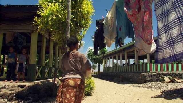 Young Samoan woman hanging laundry on a line near her home