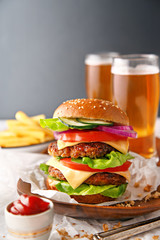Tasty hamburger with french fries and beer in the background