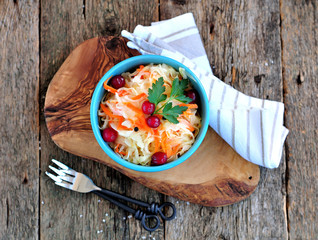 Marinated organic cabbage with carrots, vinegar, sugar and salt on an old wooden background.