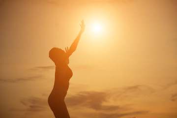 Silhouette of woman praying over beautiful sky background