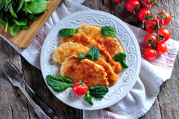Schnitzel from chicken breast with green salad, rustic style.