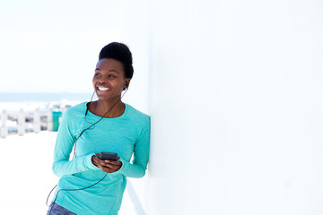 young woman smiling with mobile phone and earphones