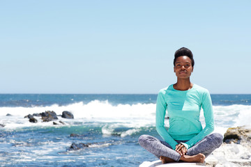 young african american woman doing yoga at the beach
