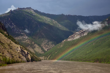 Rainbow above the muddy river in the mountains. The River Indigirka. The Republic Of Sakha. Russia.