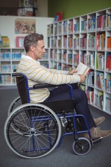 Obraz premium Attentive disabled school teacher reading book in library