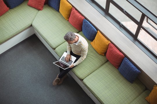Overhead view of school teacher using laptop in library