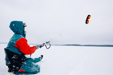 Snowkiting.  Male athlete skier rides a kite skiing on a frozen lake. The Kola Peninsula.