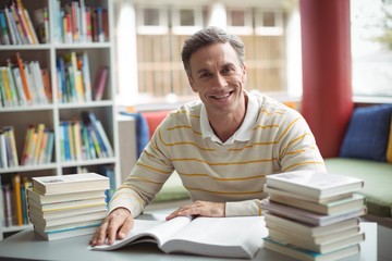 Portrait of school teacher reading book in library