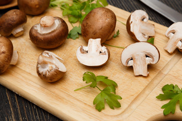 Raw royal champignons with green leaves on rustic board.