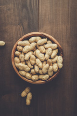many roasted peanuts in wooden bowl on the table background