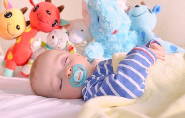 Cute baby is sweetly sleeping with his stuffed toys
