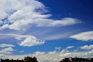 Fototapeta premium Chmury na błękitnym niebie nad budynkami mieszkalnymi.