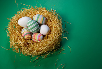 Colorful vintage easter eggs in nest on green background