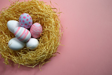 Naklejka na ściany i meble Colorful vintage easter eggs in nest on pink background