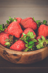 wooden bowl full of fresh strawberries on the brown table