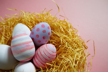 Colorful vintage easter eggs in nest on pink background