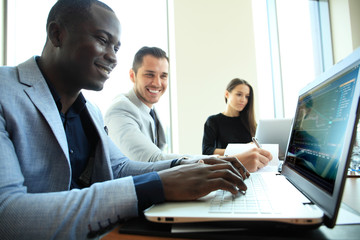Image of young African businessman looking at camera at workplace