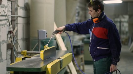 Carpenter using air nozzles gun to clean workplace