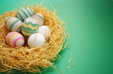 Colorful vintage easter eggs in nest on green background